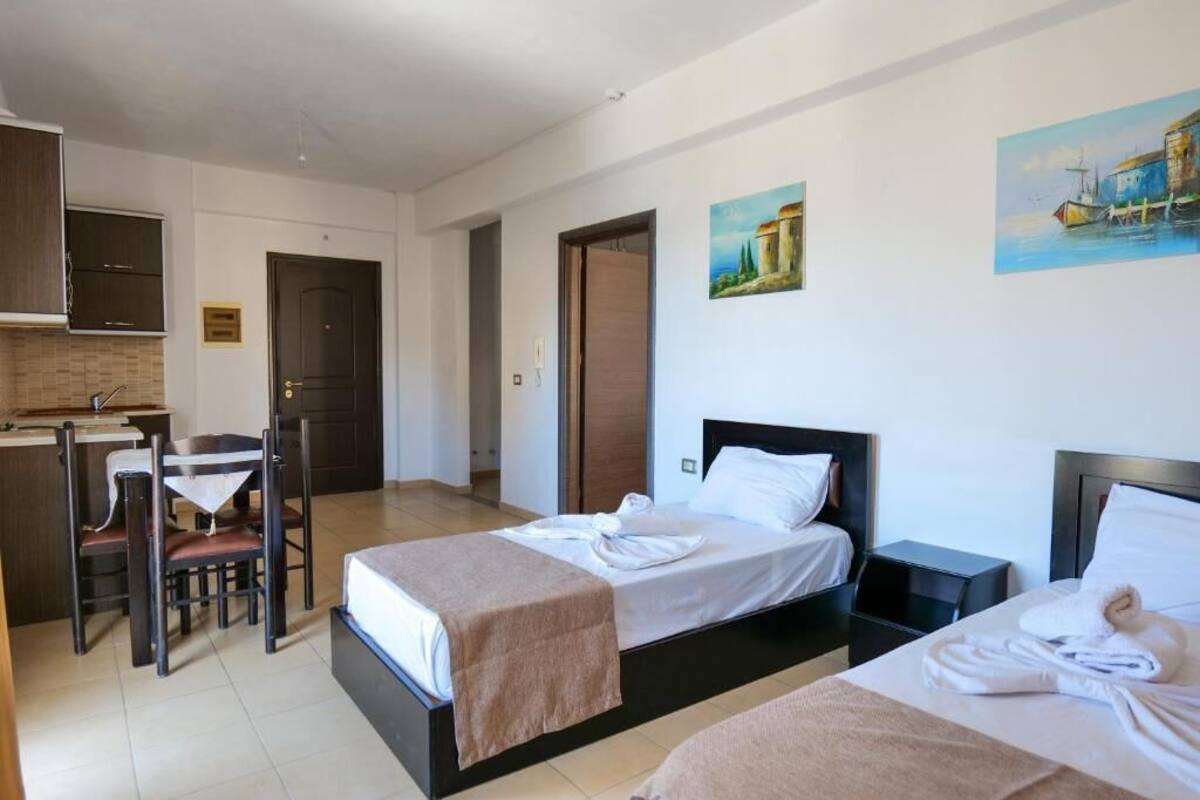 Habitació d'hotel amb un llit, una taula de nit i una cadira. Hi ha una porta, un quadre a la paret i una finestra.