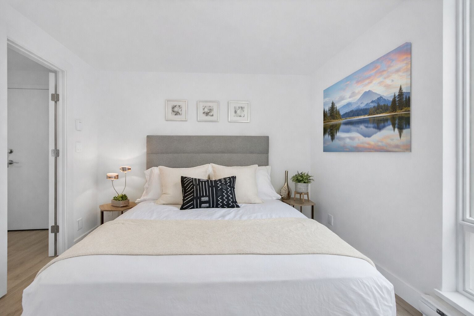 Ein Schlafzimmer mit Bett, Nachttischen, einem Wandbild und einer Tür.