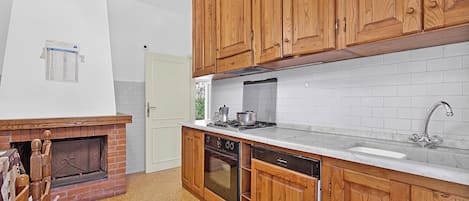 Une cuisine avec des meubles en bois, un four encastré, un lave-vaisselle et un crédence en carrelage blanc.
