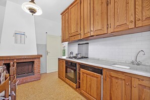 A kitchen with wooden cabinets, a built-in oven, a dishwasher, and a white tiled backsplash. - Casa Colombo With Garden In Forte Dei Marmi (Forte dei Marmi)