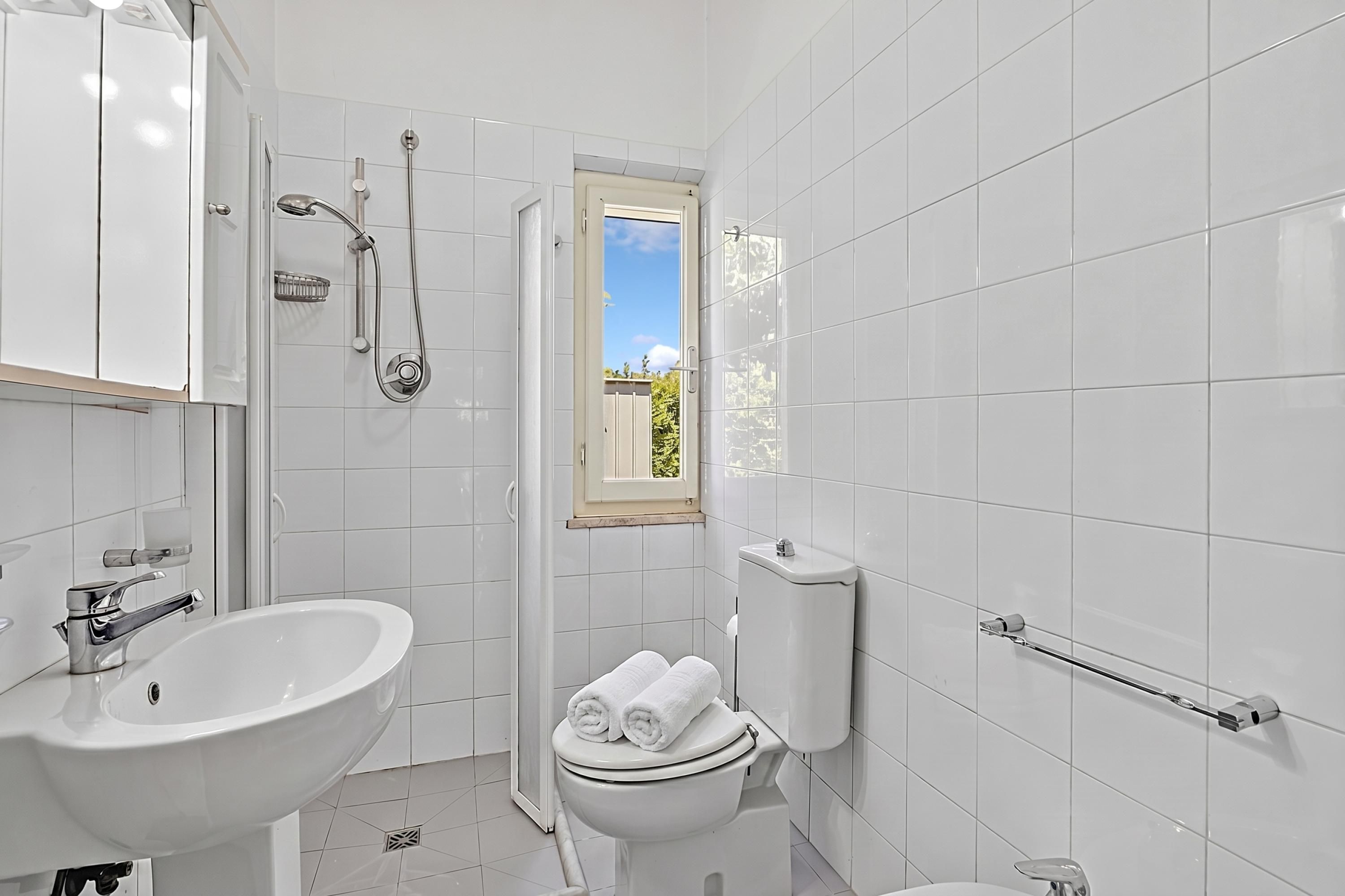 Un baño moderno con ducha, inodoro, lavabo y ventana con vistas.