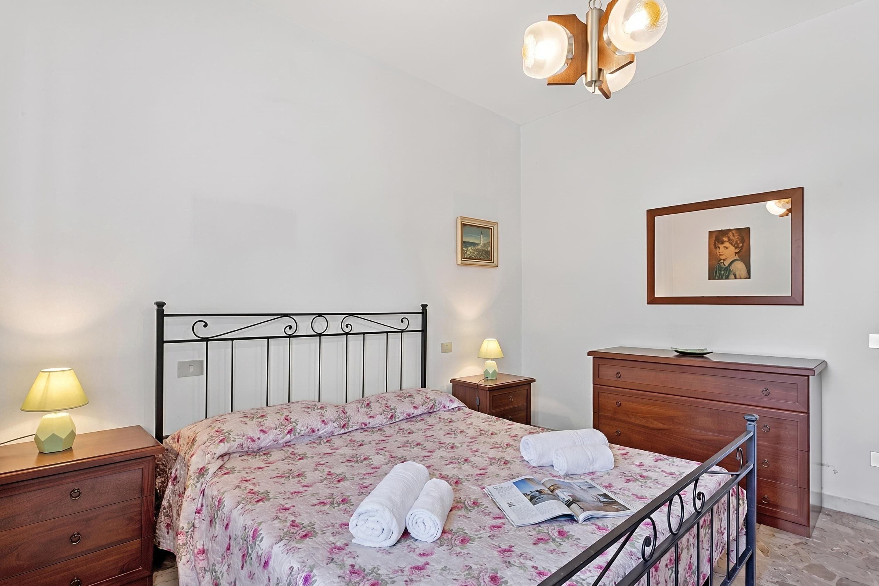 A bedroom with a bed, bedside tables, a dresser, and a mirror.