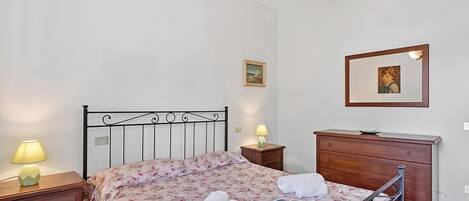 A bedroom with a bed, bedside tables, a dresser, and a mirror.