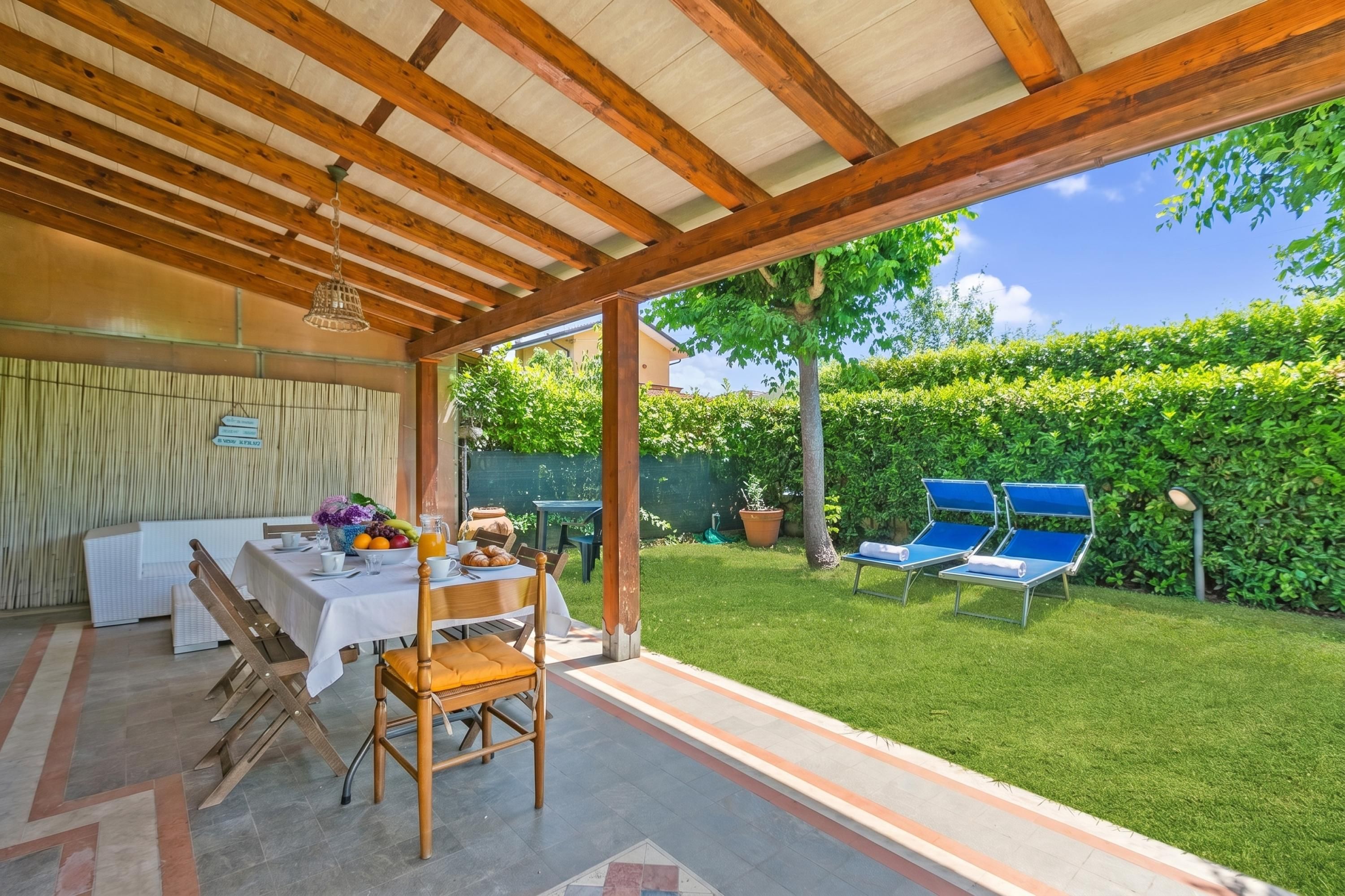 Eine Terrassenanlage mit Esstisch, überdachter Sitzgruppe und Blick auf einen gepflegten Garten.