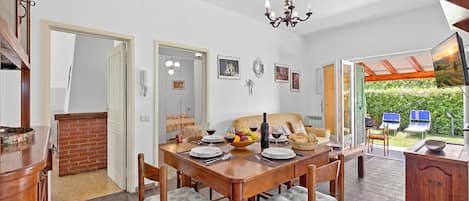 Un coin repas avec une table en bois, des chaises et un lustre.