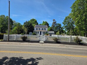 A two-story house with a white picket fence, a driveway, and a street. - Welcoming 4-bedroom house in charming Scituate. Perfect for a family trip (Scituate)