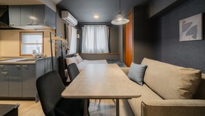 A compact living space with a kitchenette, dining table, sofa, and a window with curtains. - HOTEL LEGALIE Osaka Shinsaibashi North (Osaka)