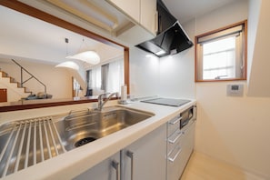 A modern kitchen with a stainless steel sink, a built-in oven, and a window with a view. - HOTEL LEGALIE Osaka Shinsaibashi North (Osaka)