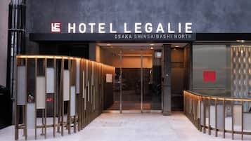 The entrance to Hotel Legalie with a modern design, including a glass door and a metal railing.