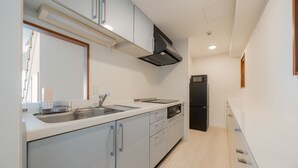 A modern kitchen with a dishwasher, sink, and black refrigerator. - HOTEL LEGALIE Osaka Shinsaibashi North (Osaka)