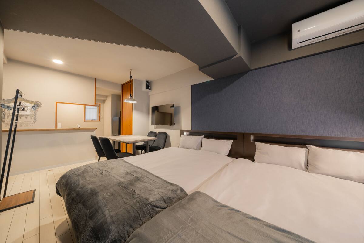 Habitación de hotel con una cama grande, un escritorio y una silla. Hay un televisor montado en la pared y un equipo de aire acondicionado arriba.
