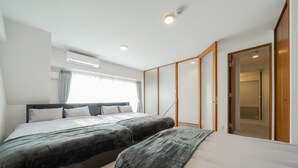 A modern hotel room with two beds, a large window with curtains, an air conditioning unit, and a wooden wardrobe. - HOTEL LEGALIE Osaka Shinsaibashi North (Osaka)