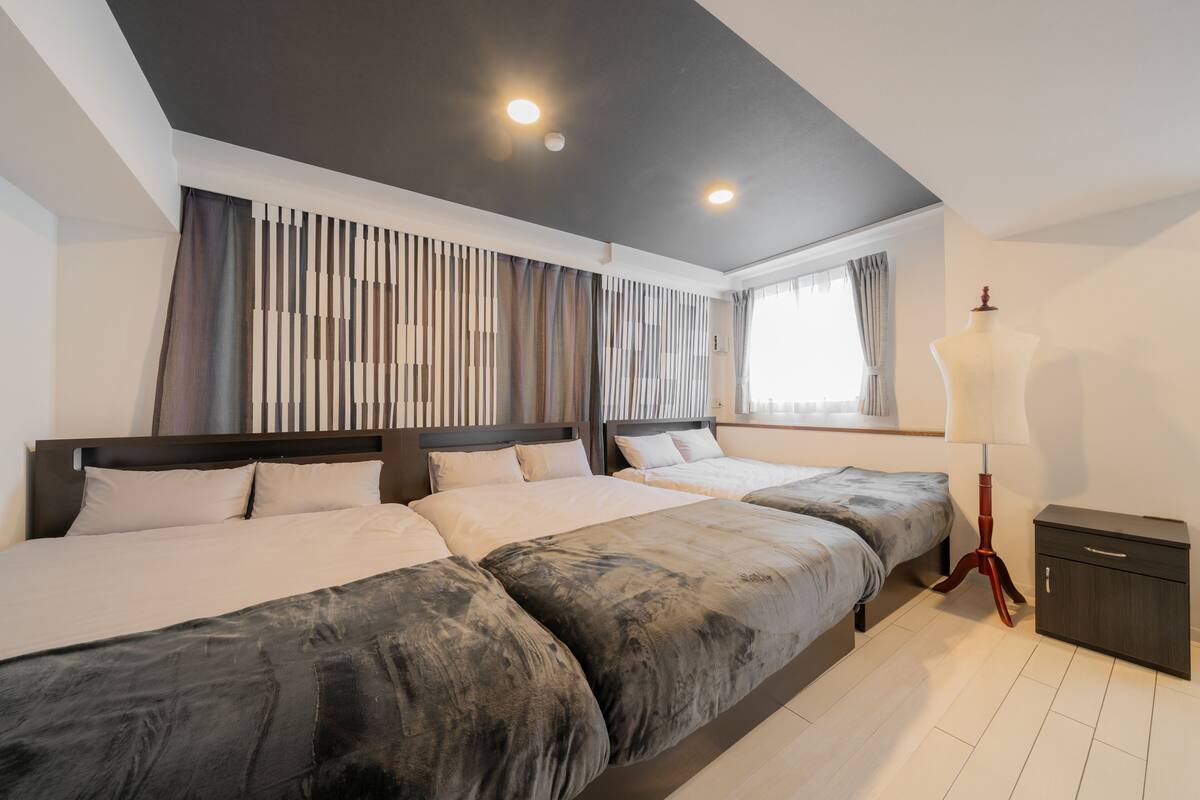 Una habitación de hotel moderna con una cama grande, una mesita de noche, una lámpara y un armario.