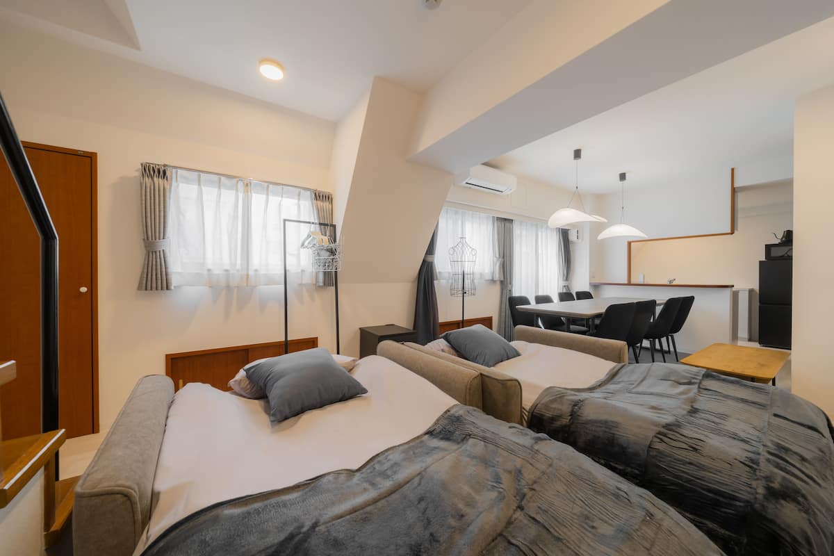 Una habitación de hotel con dos camas, un escritorio, una silla y una zona de comedor.