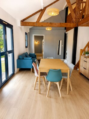 A dining area with a wooden table and chairs, a sofa, and a staircase.