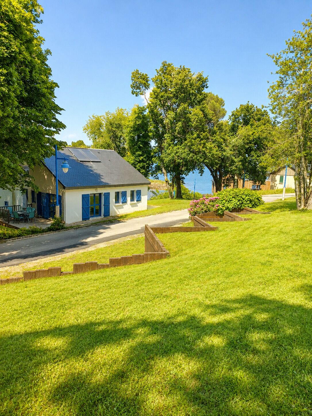 A residential area with a house featuring a blue door and windows, a paved driveway, and a well-maintained lawn.