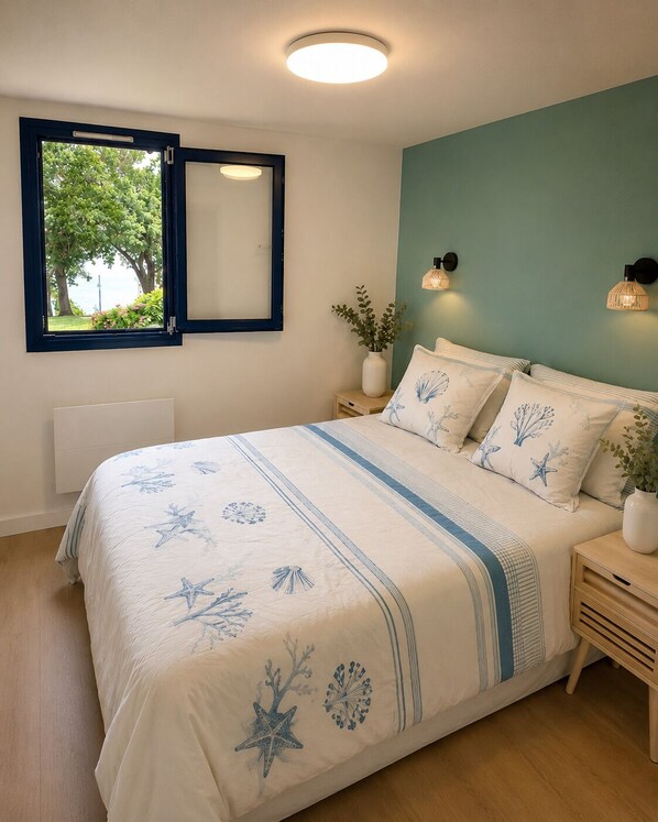 A bedroom with a bed, bedside tables, a window with a view, and wall-mounted lighting.