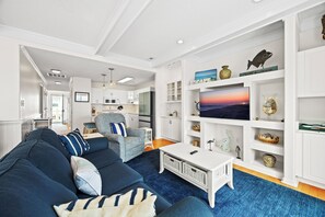 Ein modernes Wohnzimmer mit einer Couch, einem Couchtisch und dekorativen Gegenständen auf Regalen.
