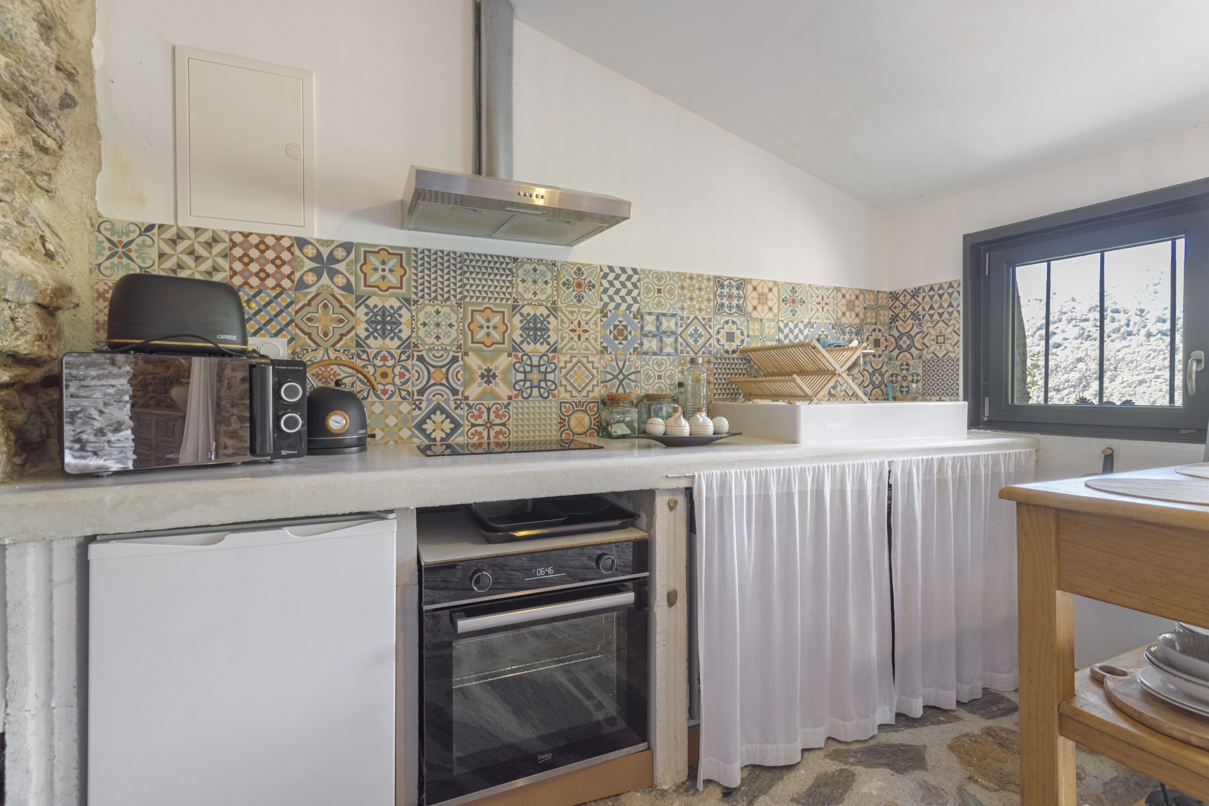 A compact kitchen with a built-in oven, a toaster, and a coffee maker on the counter.
