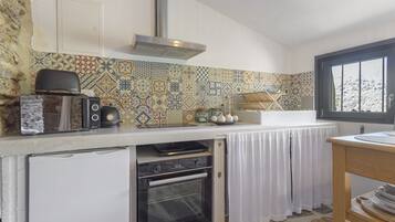 A compact kitchen with a built-in oven, a toaster, and a coffee maker on the counter.