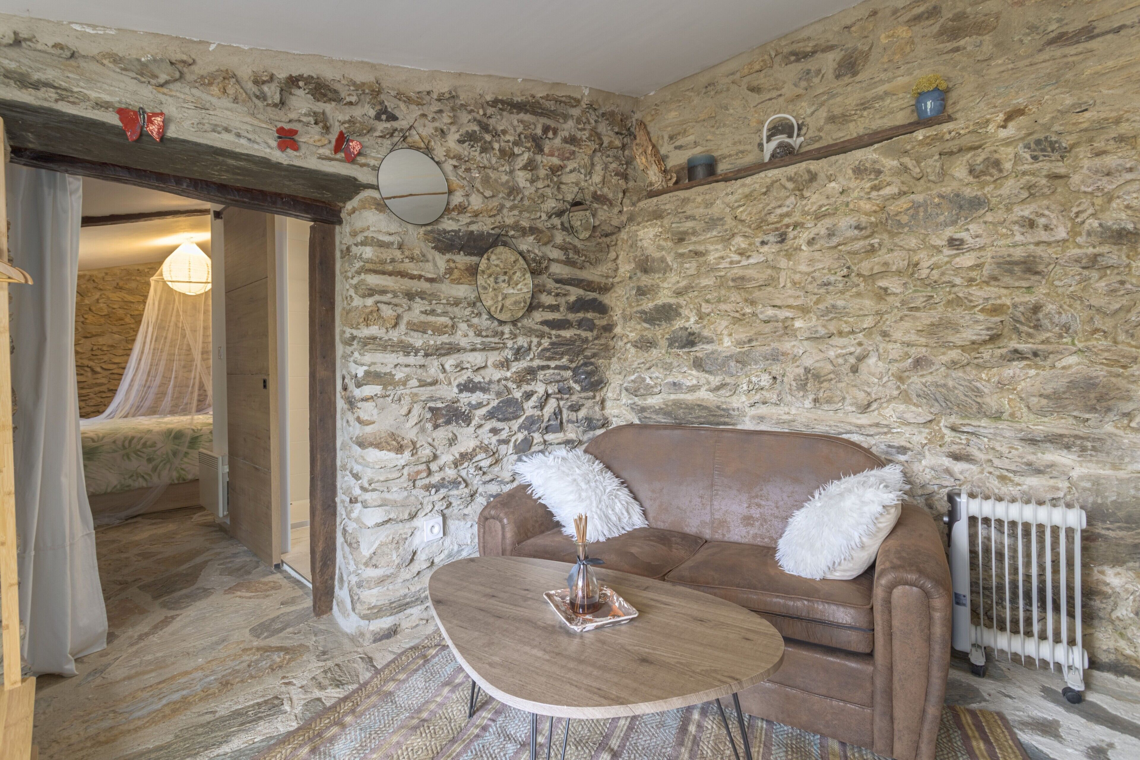 A stone-walled room with a brown leather sofa, a wooden coffee table, and a white radiator.