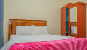 Ein Bett mit einem Holz-Kopfteil, weißen Kissen und einer rosa Decke.
