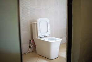 A white toilet with a closed lid in a bathroom with tiled walls and floor.