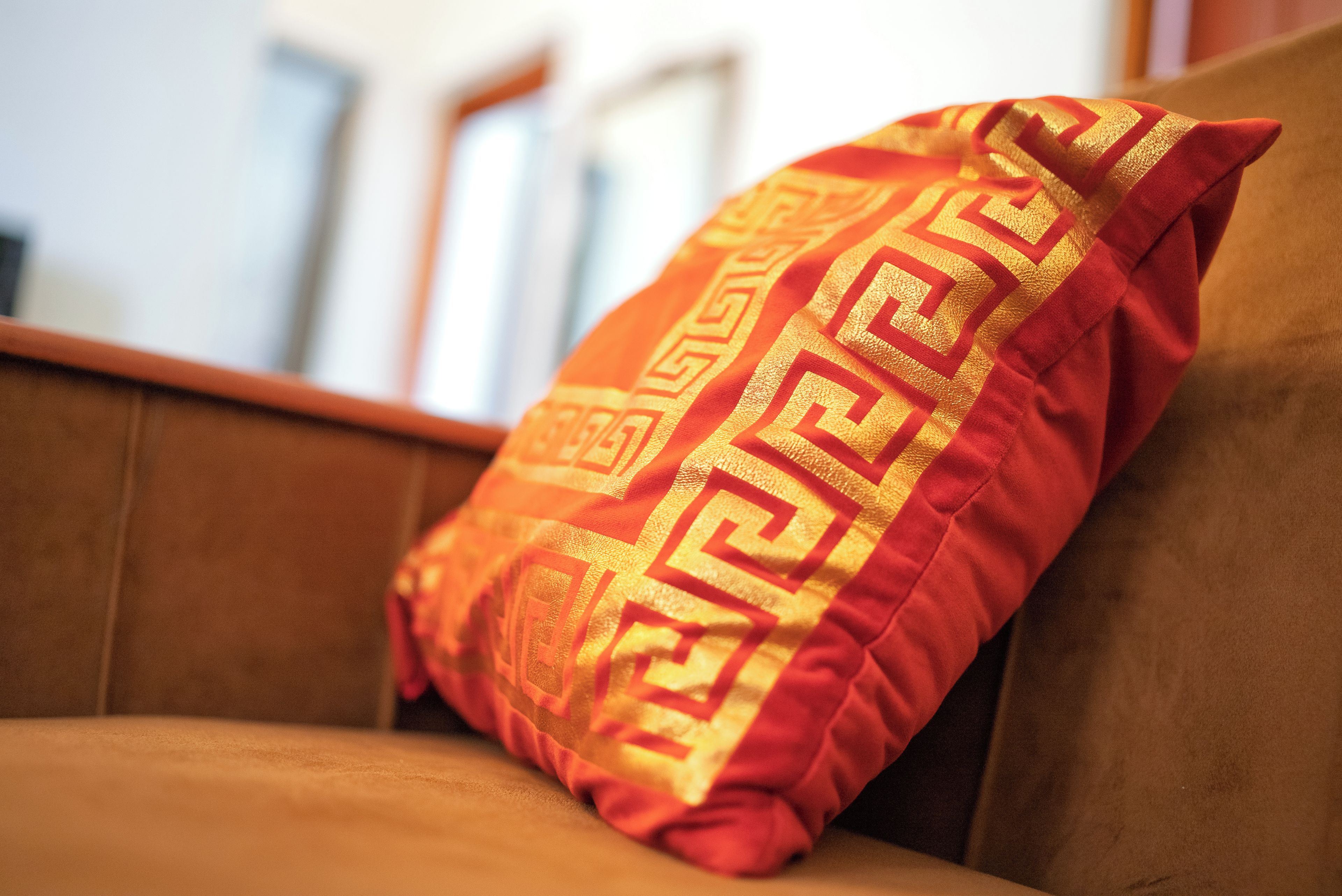 Un canapé marron agrémenté d’un seul coussin décoratif orné d’un motif géométrique.