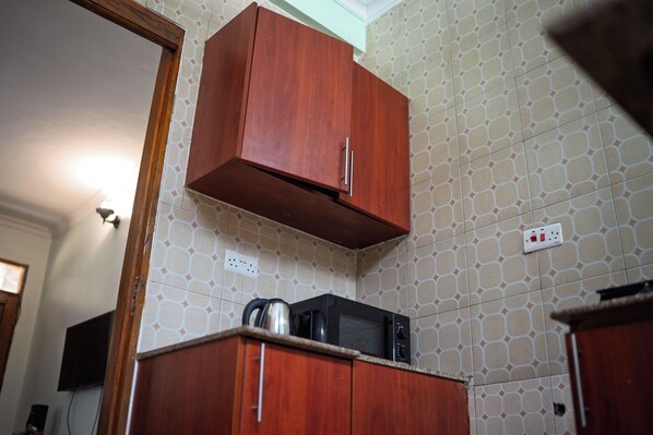 A kitchen with wooden cabinets, a microwave, and patterned wall tiles.