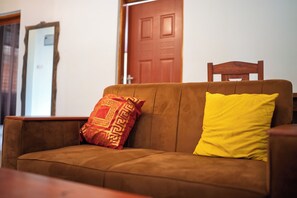 A brown sofa with a patterned cushion and a solid yellow cushion.
