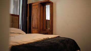 Une chambre à coucher avec un lit, une armoire en bois et une fenêtre avec des rideaux.