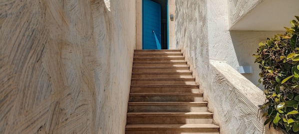 A narrow stone staircase leading to a blue door, surrounded by stone walls and a small plant. - Borgo Rio Favara 6 - Moon (Ispica)