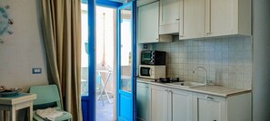 A compact kitchen with a microwave, stove, and sink. - Borgo Rio Favara 6 - Moon (Ispica)