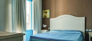 A bedroom with a bed, a nightstand, a wall-mounted lamp, and a window with curtains. - Borgo Rio Favara 6 Luna (Sicilia)