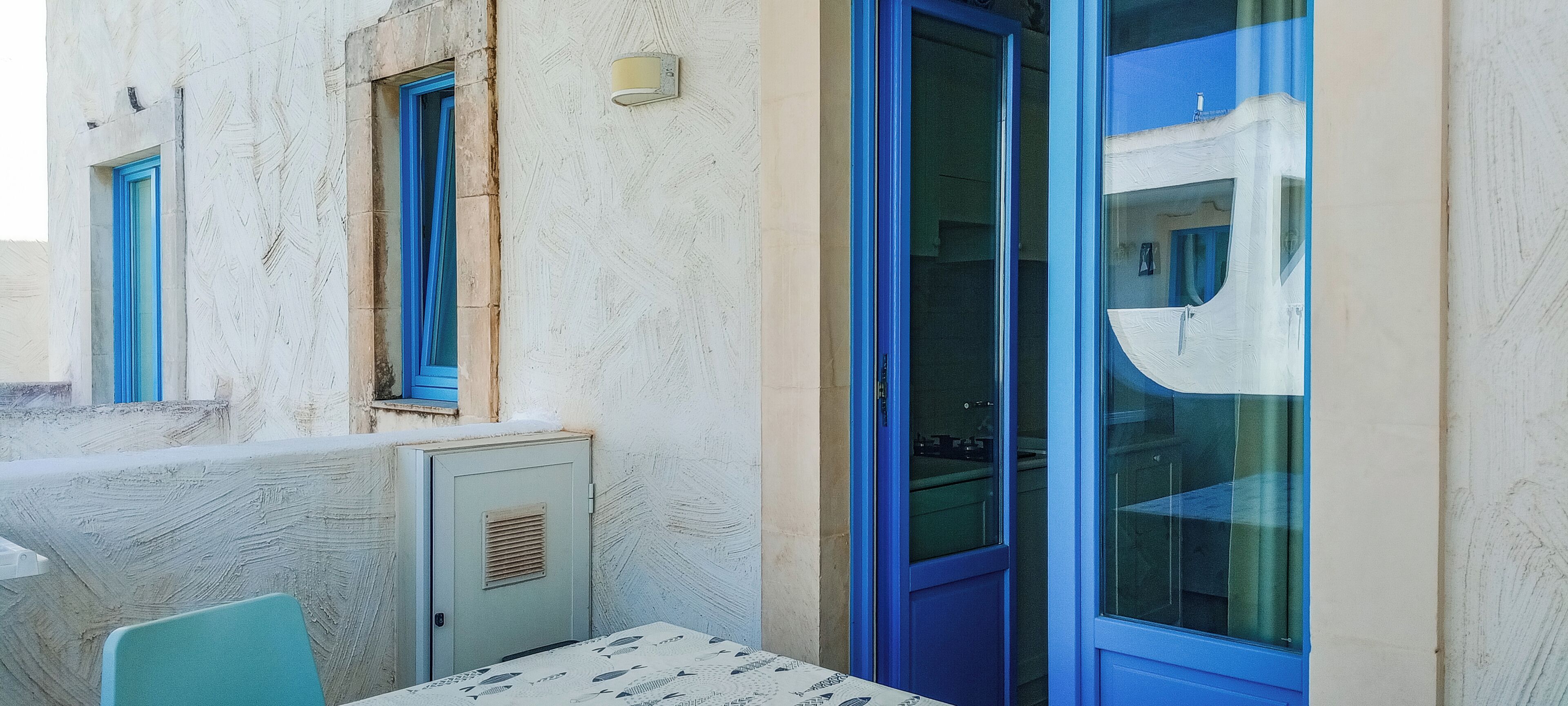 A room with a table, chairs, a blue door, and a window.
