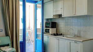 A compact kitchen with a microwave, stove, and sink. - Borgo Rio Favara 6 Luna (Sicilia)