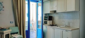 A compact kitchen with a microwave, stove, and sink. - Borgo Rio Favara 6 Luna (Sicilia)