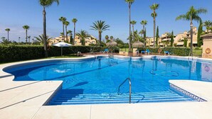 A swimming pool with clear blue water, surrounded by palm trees and lounge chairs. - 250m² PENTHOUSE DUPLEX- Marbella: 3 bedrooms, 3 bathrooms, solarium, close to the sea, golf courses (marbella)