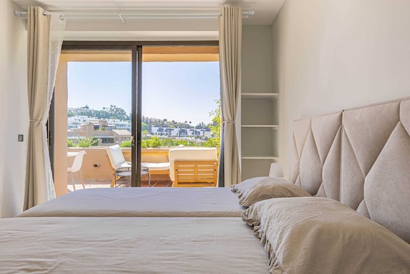 A bedroom with a bed, a view of a balcony, and a cityscape in the background. - 250m² PENTHOUSE DUPLEX- Marbella: 3 bedrooms, 3 bathrooms, solarium, close to the sea, golf courses (marbella)