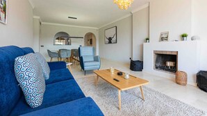 A modern living room with a blue sofa, a wooden coffee table, and a fireplace. - 250m² PENTHOUSE DUPLEX- Marbella: 3 bedrooms, 3 bathrooms, solarium, close to the sea, golf courses (marbella)