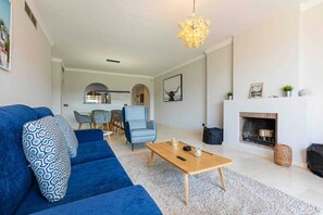 A modern living room with a blue sofa, a wooden coffee table, and a fireplace. - 250m² PENTHOUSE DUPLEX- Marbella: 3 bedrooms, 3 bathrooms, solarium, close to the sea, golf courses (marbella)