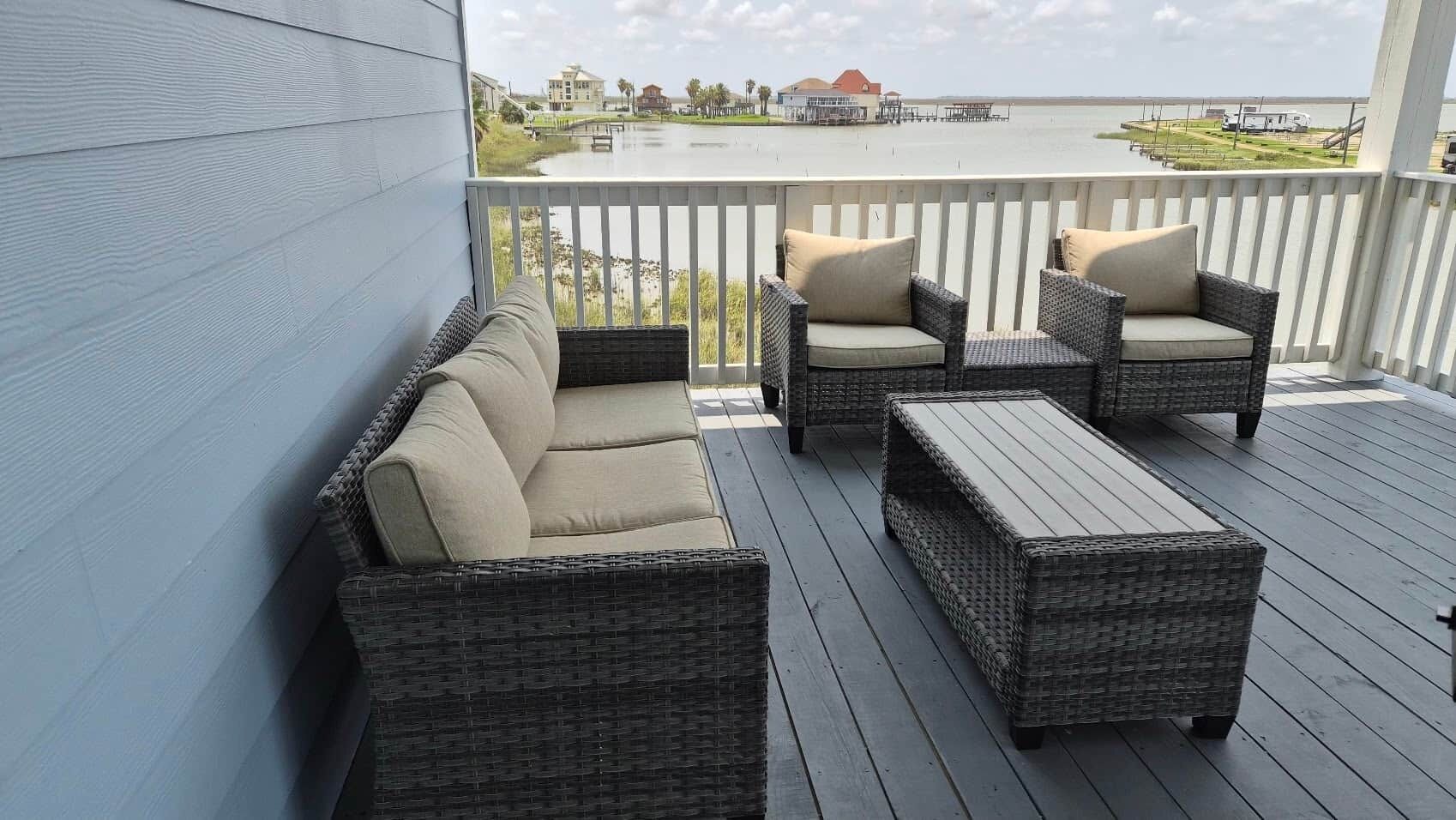 Een overdekt terras met rieten meubels en uitzicht op het water.