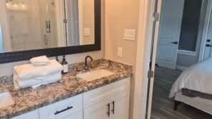 A bathroom with a sink, mirror, and towel stack.