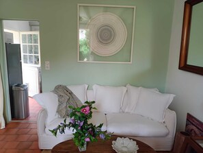 Ein Wohnzimmer mit einem weißen Sofa, einem Holztisch und einem gerahmten Kunstwerk an der Wand.