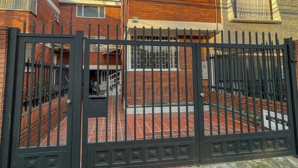 A gated residential area with brick houses, a visible gate, and a clear sky. - Apartment near the airport, modern shopping malls and entertainment centers (Bogotá)