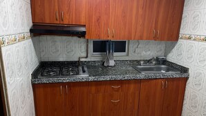 A kitchen with wooden cabinets, a gas stove, a sink, and a microwave. - Apartment near the airport, modern shopping malls and entertainment centers (Bogotá)