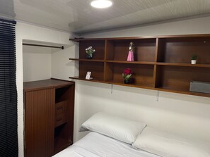 Een slaapkamer met een bed, een houten garderobe en een plank met decoratieve objecten.