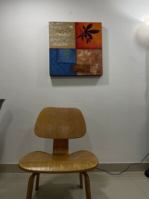 A wooden chair in a room with a textured wall art piece above it. - Apartment near the airport, modern shopping malls and entertainment centers (Bogotá)