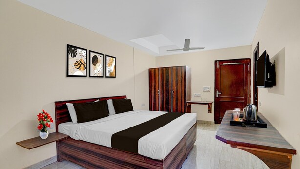A hotel room with a bed, a TV, a wardrobe, and a small table with a kettle. - Classic Global Tower (Mathura)