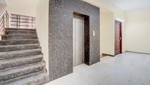 A modern interior with a marble staircase, a door, and a tiled floor. - Classic Global Tower (Mathura)